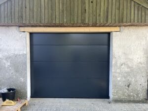 Ny mørkegrå garageport installeret i betonmur