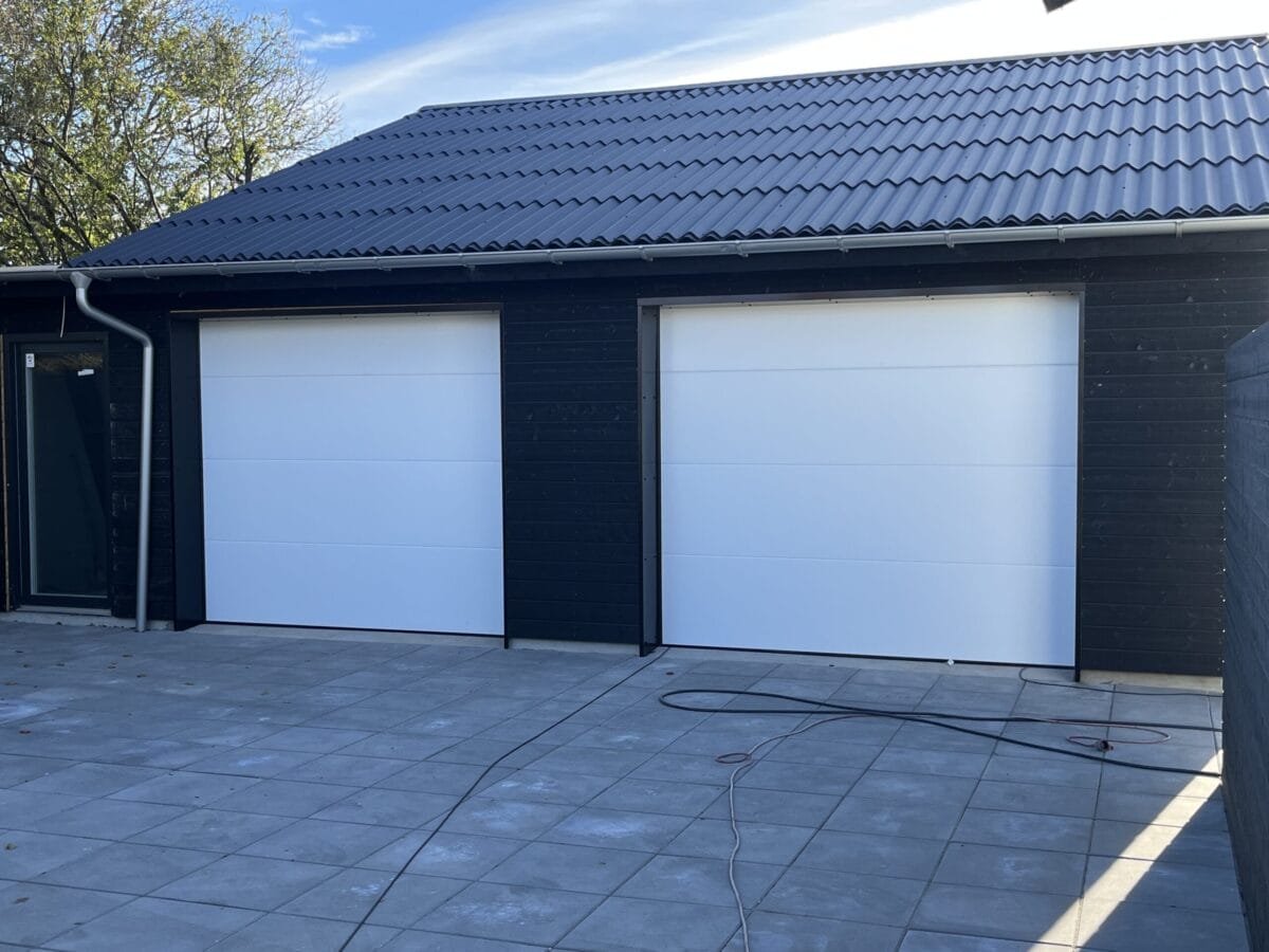 Sort garage med to hvide porte